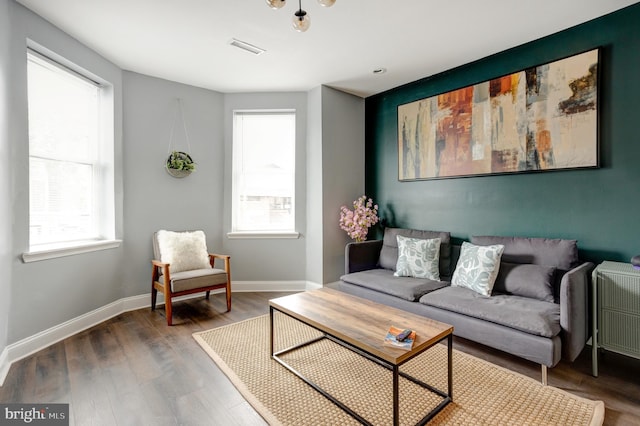 living room featuring baseboards, plenty of natural light, visible vents, and wood finished floors