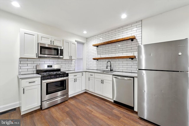 kitchen featuring stainless steel appliances, dark wood-type flooring, a sink, visible vents, and tasteful backsplash