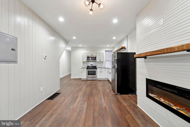 kitchen with visible vents, decorative backsplash, dark wood-style floors, appliances with stainless steel finishes, and a fireplace