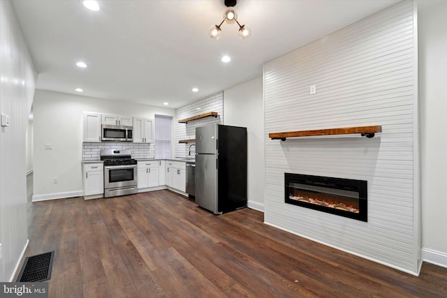 kitchen featuring dark wood-style floors, stainless steel appliances, tasteful backsplash, visible vents, and a large fireplace