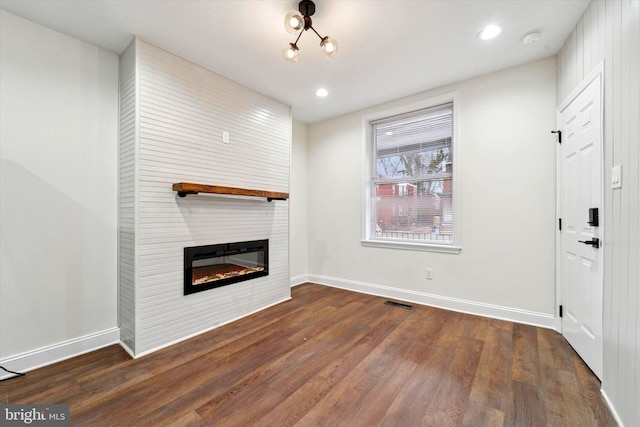 unfurnished living room featuring a fireplace, baseboards, and wood finished floors