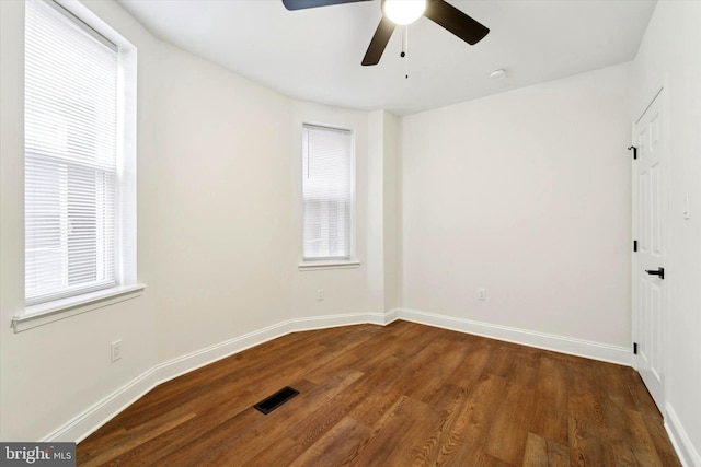 unfurnished room featuring visible vents, plenty of natural light, baseboards, and wood finished floors