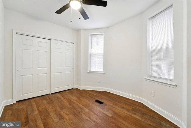 unfurnished bedroom featuring baseboards, a closet, visible vents, and dark wood-type flooring