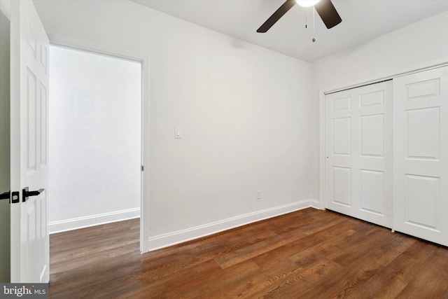 unfurnished bedroom with ceiling fan, a closet, baseboards, and dark wood-style flooring