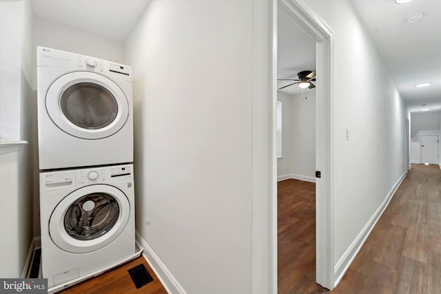 laundry room featuring ceiling fan, baseboards, stacked washer / drying machine, and wood finished floors