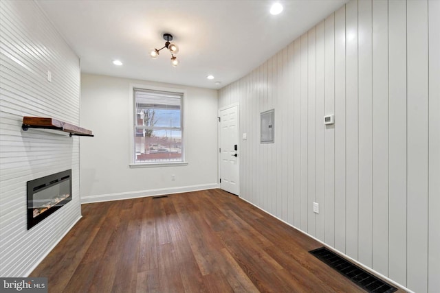 entryway with a fireplace, dark wood finished floors, visible vents, and electric panel