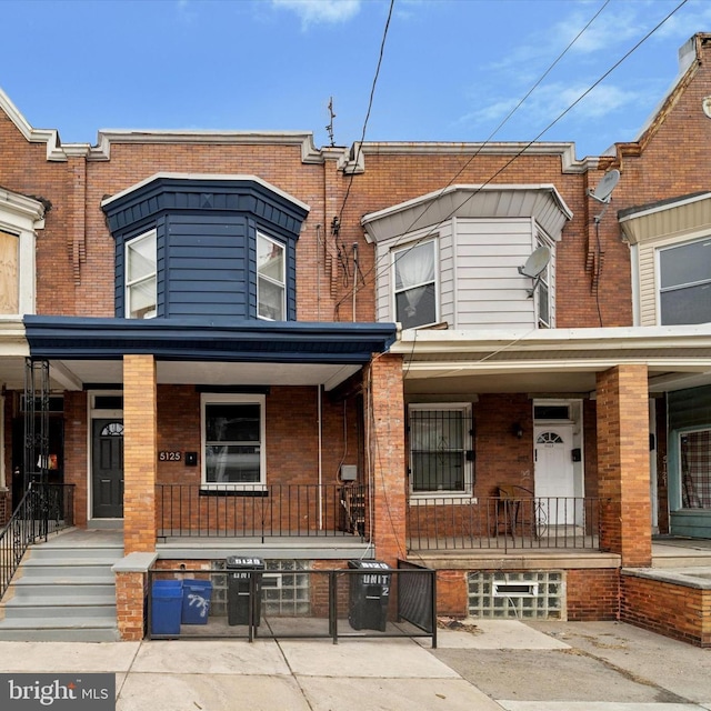 multi unit property featuring covered porch and brick siding