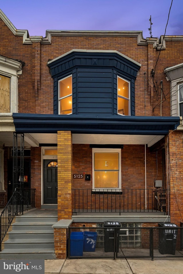 view of front of property with covered porch, cooling unit, and brick siding