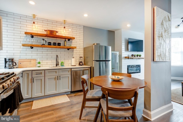 kitchen featuring a sink, stainless steel appliances, gray cabinets, and light wood-style floors