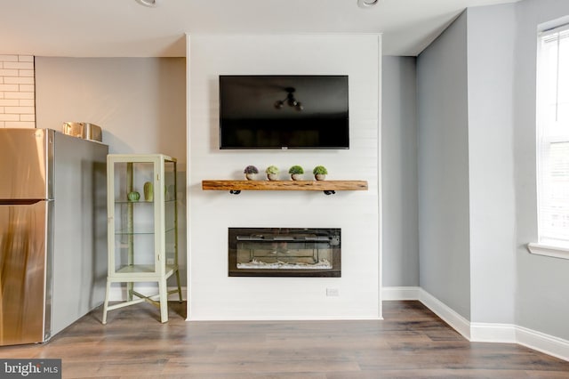 unfurnished living room featuring wood finished floors, a glass covered fireplace, and baseboards