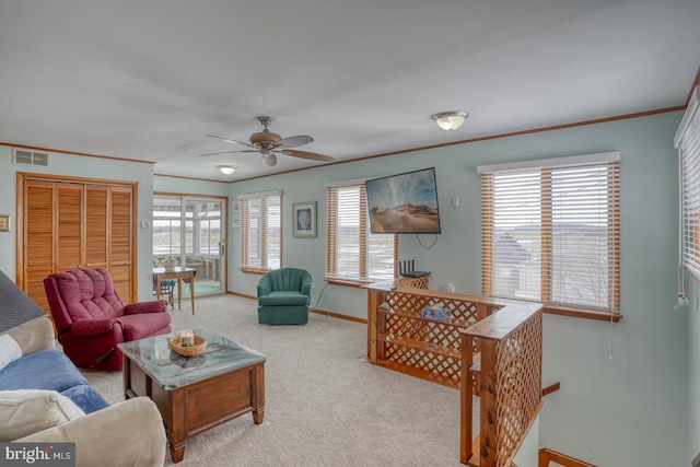 living room featuring a ceiling fan, baseboards, visible vents, carpet floors, and crown molding