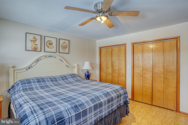 bedroom with ceiling fan, multiple closets, and wood finished floors