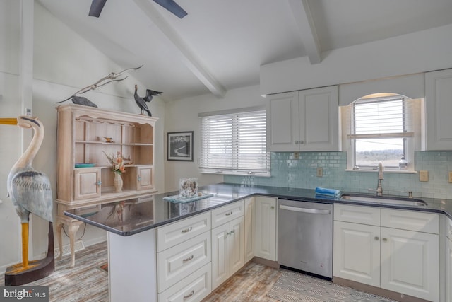 kitchen with a peninsula, plenty of natural light, a sink, dishwasher, and tasteful backsplash