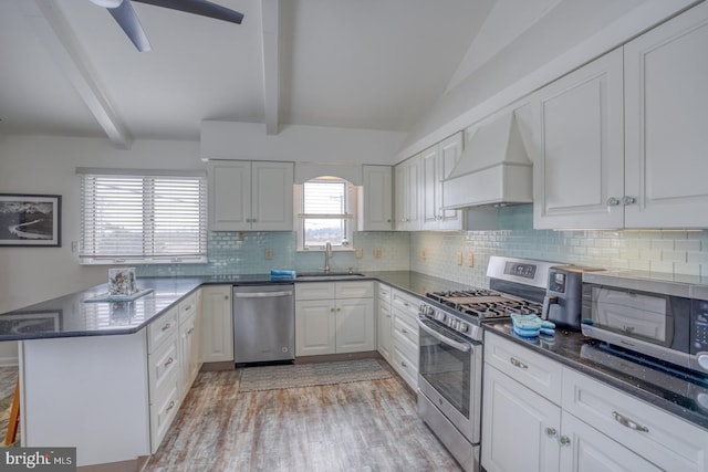 kitchen featuring custom range hood, a sink, tasteful backsplash, appliances with stainless steel finishes, and a peninsula