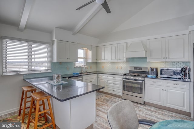 kitchen with a sink, stainless steel appliances, white cabinets, and custom range hood