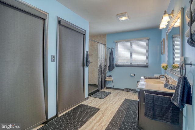 bathroom with curtained shower, vanity, wood finished floors, and baseboards