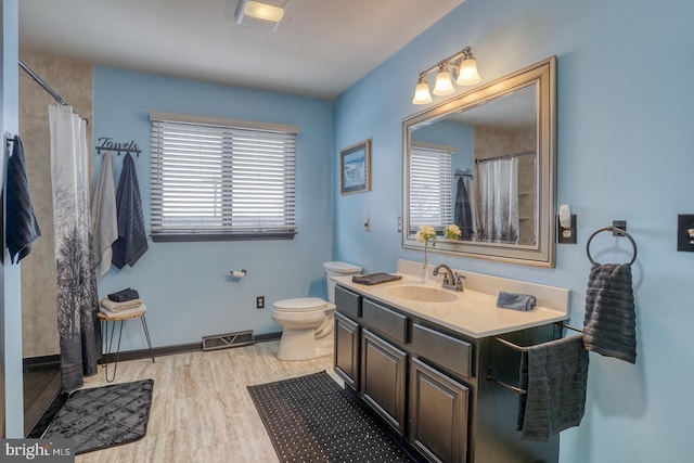 bathroom featuring vanity, wood finished floors, visible vents, baseboards, and toilet