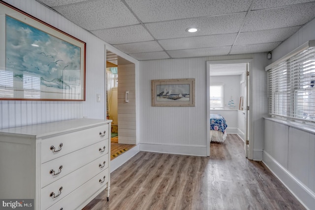 hallway featuring light wood-style flooring, baseboards, and a drop ceiling