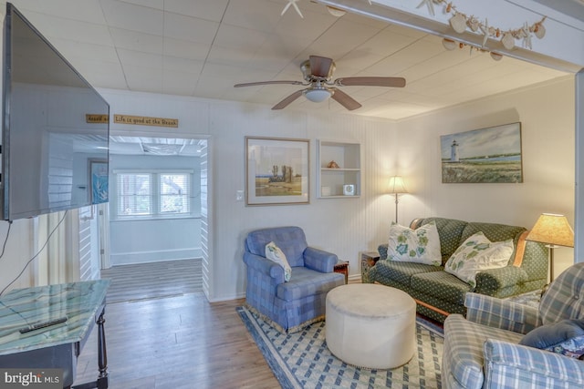 living area with ceiling fan, baseboards, wood finished floors, and ornamental molding