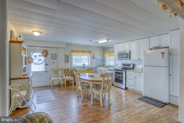 kitchen featuring light wood-style flooring, appliances with stainless steel finishes, white cabinetry, and light countertops