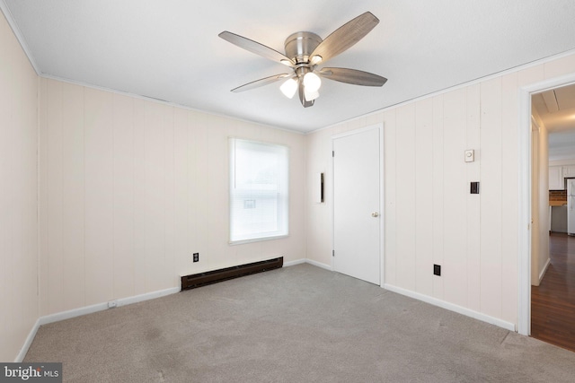 unfurnished bedroom with carpet floors, crown molding, baseboard heating, attic access, and ceiling fan