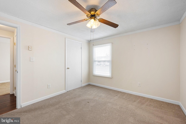 unfurnished bedroom with crown molding, carpet flooring, ceiling fan, a textured ceiling, and baseboards