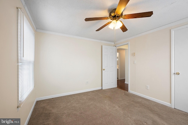 unfurnished bedroom featuring carpet floors, crown molding, a textured ceiling, and baseboards