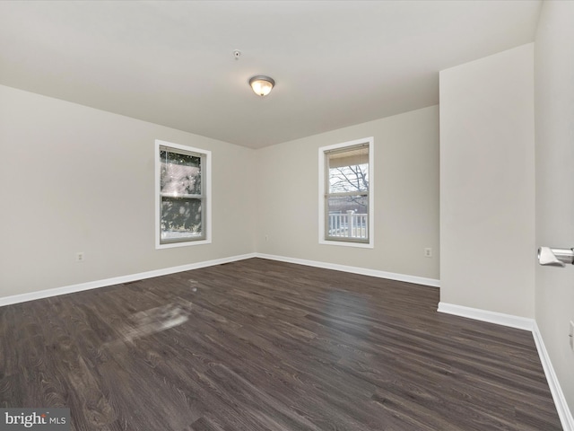 empty room with dark wood-type flooring and baseboards