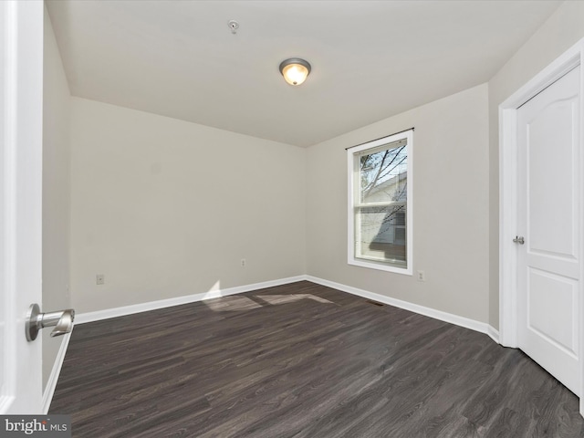 spare room with dark wood finished floors and baseboards