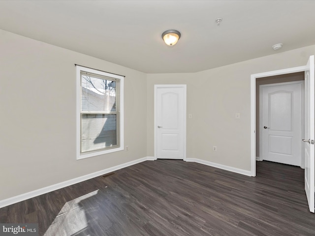 spare room featuring dark wood-style flooring and baseboards