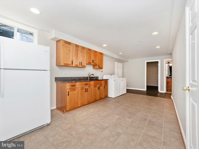 kitchen featuring recessed lighting, freestanding refrigerator, a sink, separate washer and dryer, and baseboards