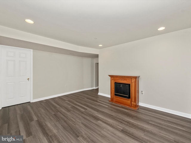 unfurnished living room with dark wood-type flooring, recessed lighting, a fireplace, and baseboards