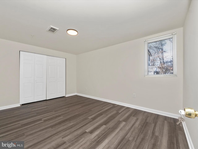 unfurnished bedroom featuring dark wood-style floors, visible vents, and baseboards