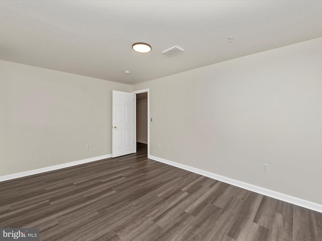 unfurnished room featuring baseboards and dark wood finished floors