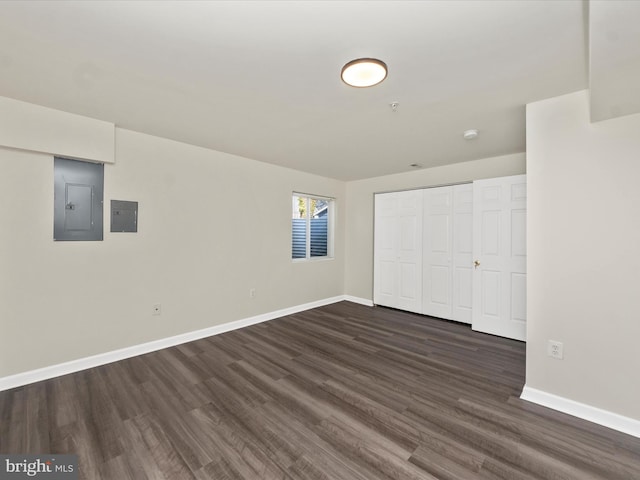 unfurnished bedroom with electric panel, baseboards, dark wood-type flooring, and a closet