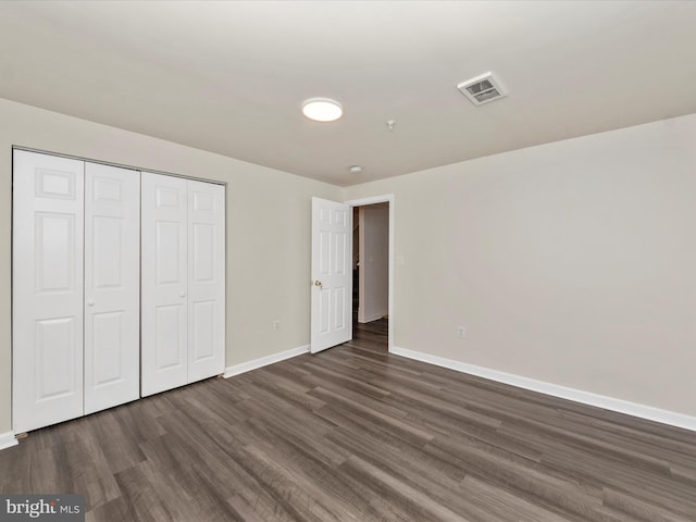 unfurnished bedroom featuring baseboards, visible vents, dark wood finished floors, and a closet