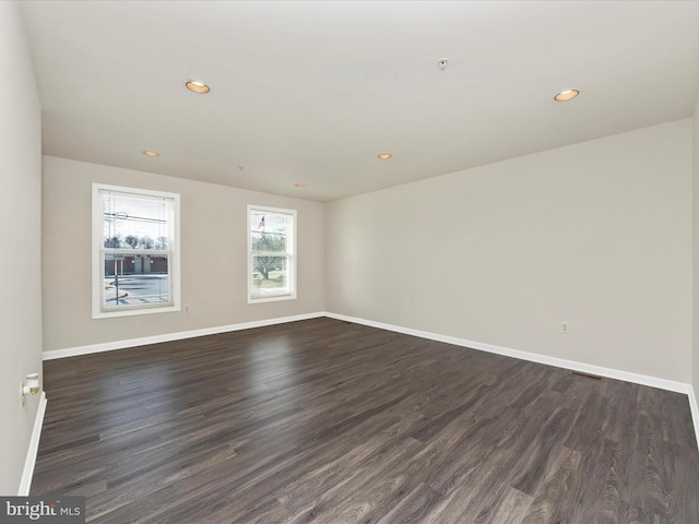 spare room featuring dark wood-style floors, recessed lighting, and baseboards