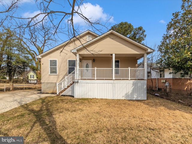 view of front of property with covered porch, a front lawn, stairway, and fence