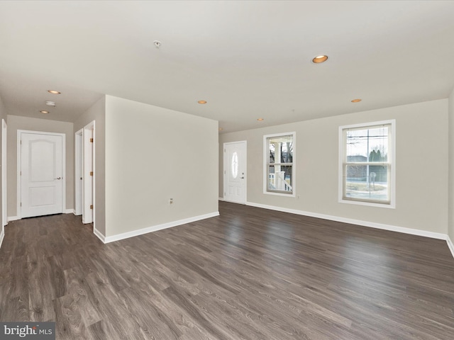 unfurnished living room with dark wood-type flooring, recessed lighting, and baseboards