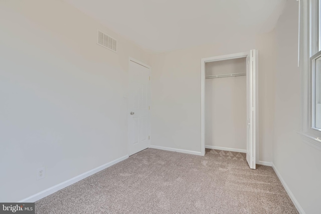 unfurnished bedroom with visible vents, light carpet, baseboards, and a closet