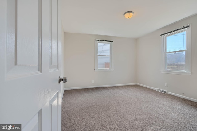 carpeted spare room featuring baseboards and visible vents