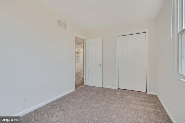 unfurnished bedroom featuring carpet flooring, baseboards, visible vents, and a closet