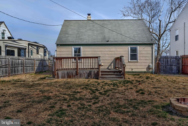 rear view of house with a deck, a fenced backyard, a lawn, and a chimney