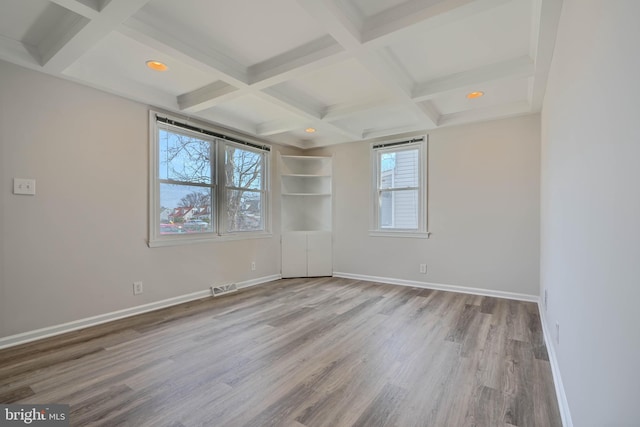 unfurnished room with wood finished floors, baseboards, visible vents, coffered ceiling, and beam ceiling