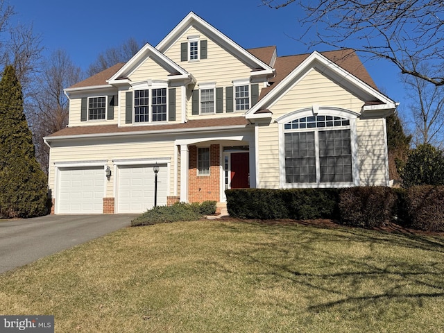 traditional-style house featuring a garage, a front lawn, aphalt driveway, and brick siding