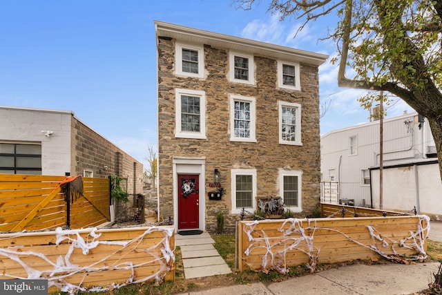 view of front facade with stone siding and fence