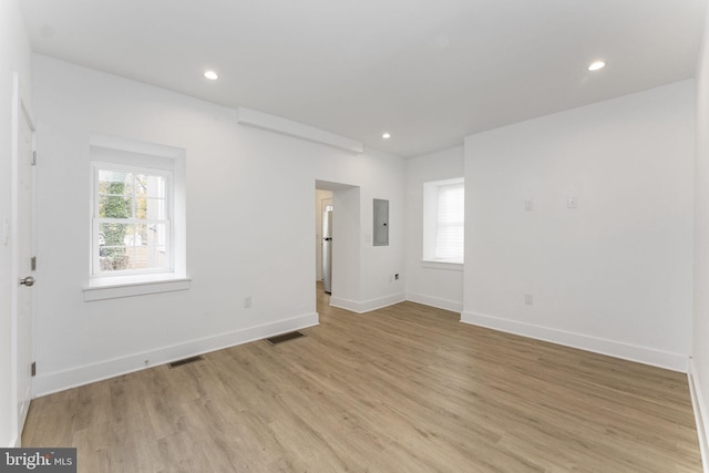 empty room with light wood-style flooring, electric panel, and recessed lighting