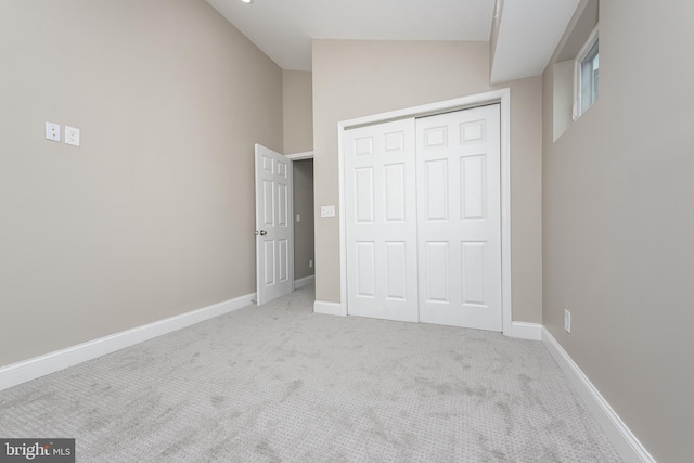 unfurnished bedroom with carpet floors, a closet, high vaulted ceiling, and baseboards