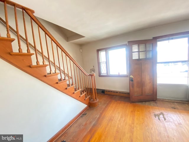 foyer featuring stairway, baseboards, a baseboard heating unit, and wood finished floors