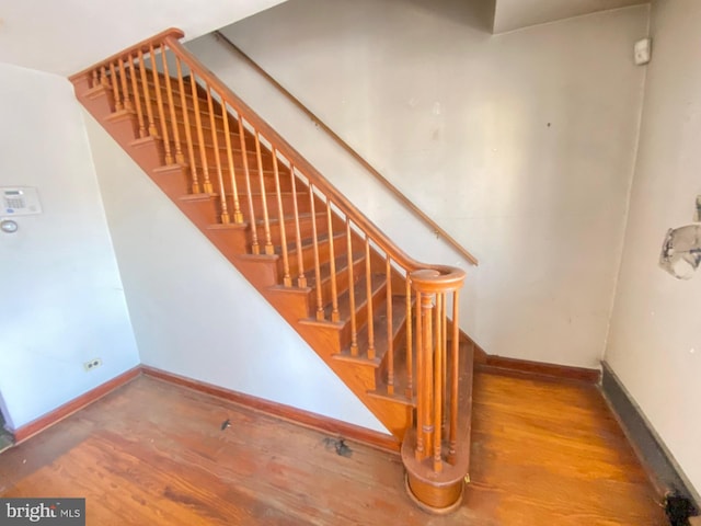 staircase featuring baseboards and wood finished floors